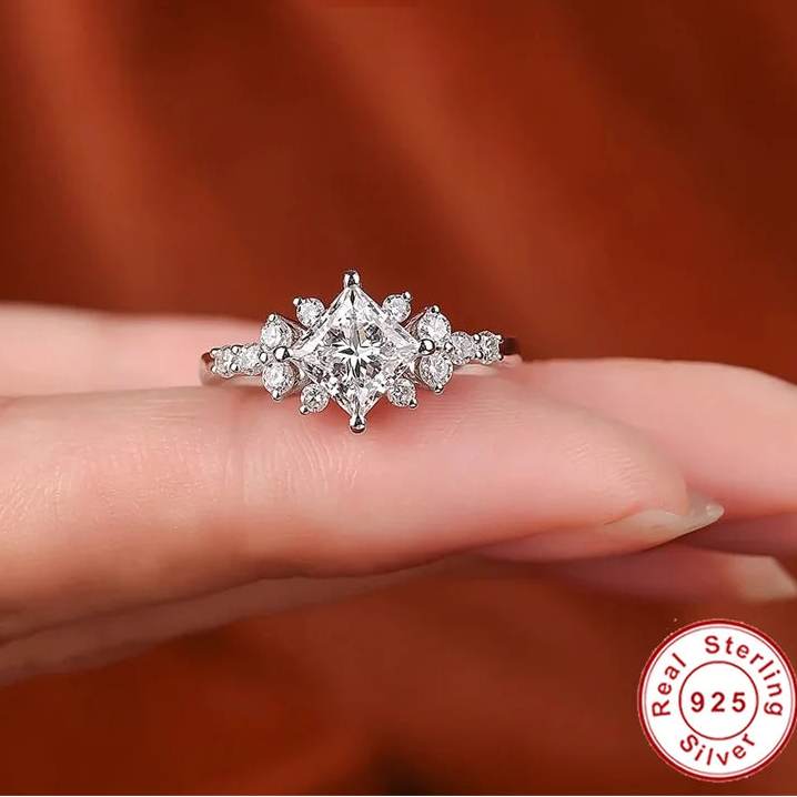 Silver ring with a princess cut moissanite on a finger