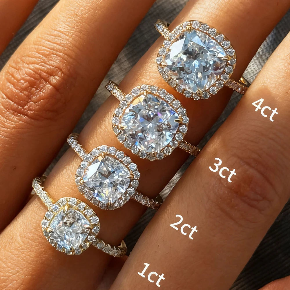 Four diamond rings on a hand with varying carat weights.