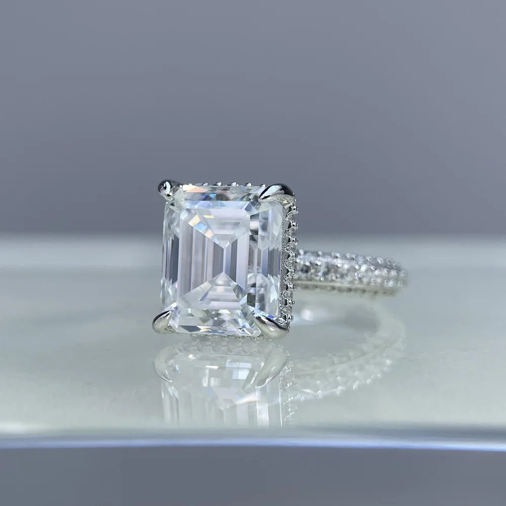 Diamond ring with a large rectangular gemstone on a reflective surface