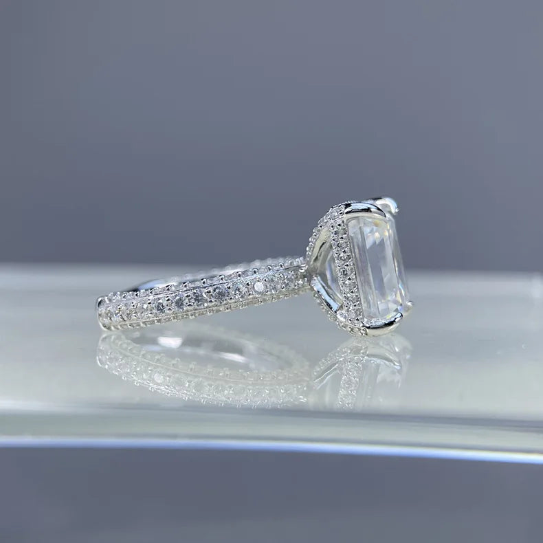 Silver ring with a large diamond and smaller diamonds on the band against a gray background