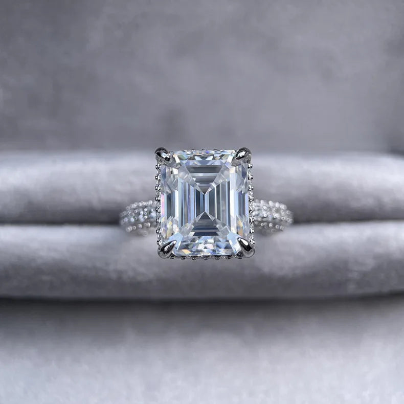 Diamond ring with emerald-cut gemstone on a gray background