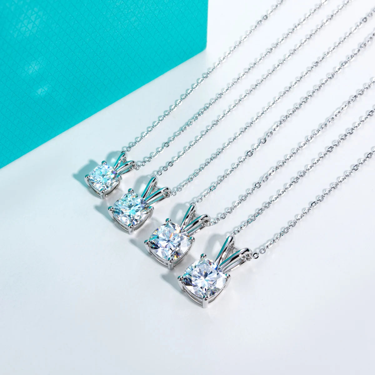 Set of silver necklaces with diamond pendants on a light blue background
