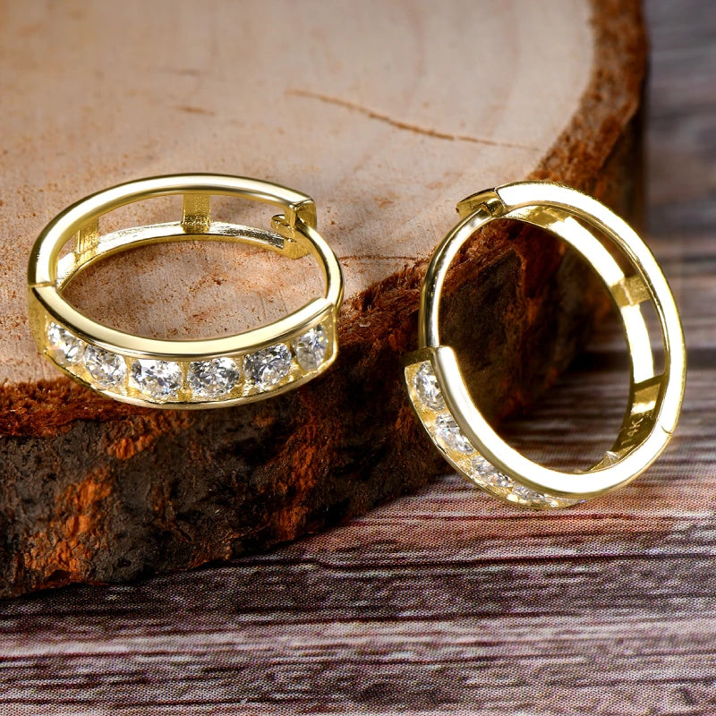 Gold hoop earrings with embedded stones on a wooden surface