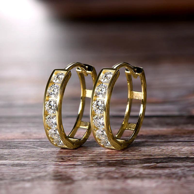 Gold hoop earrings with embedded diamonds on a wooden surface