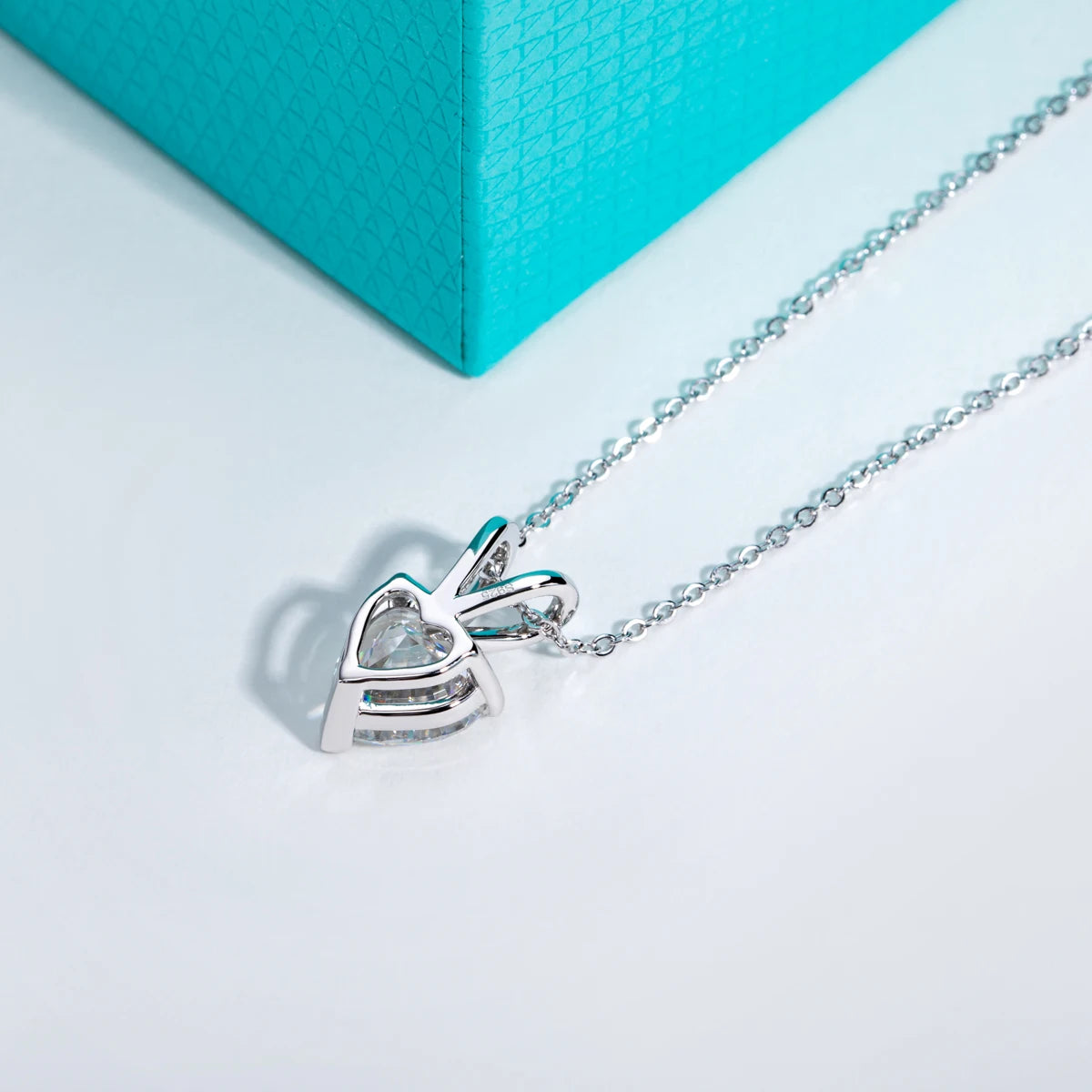 Silver necklace with a heart-shaped pendant on a light blue background