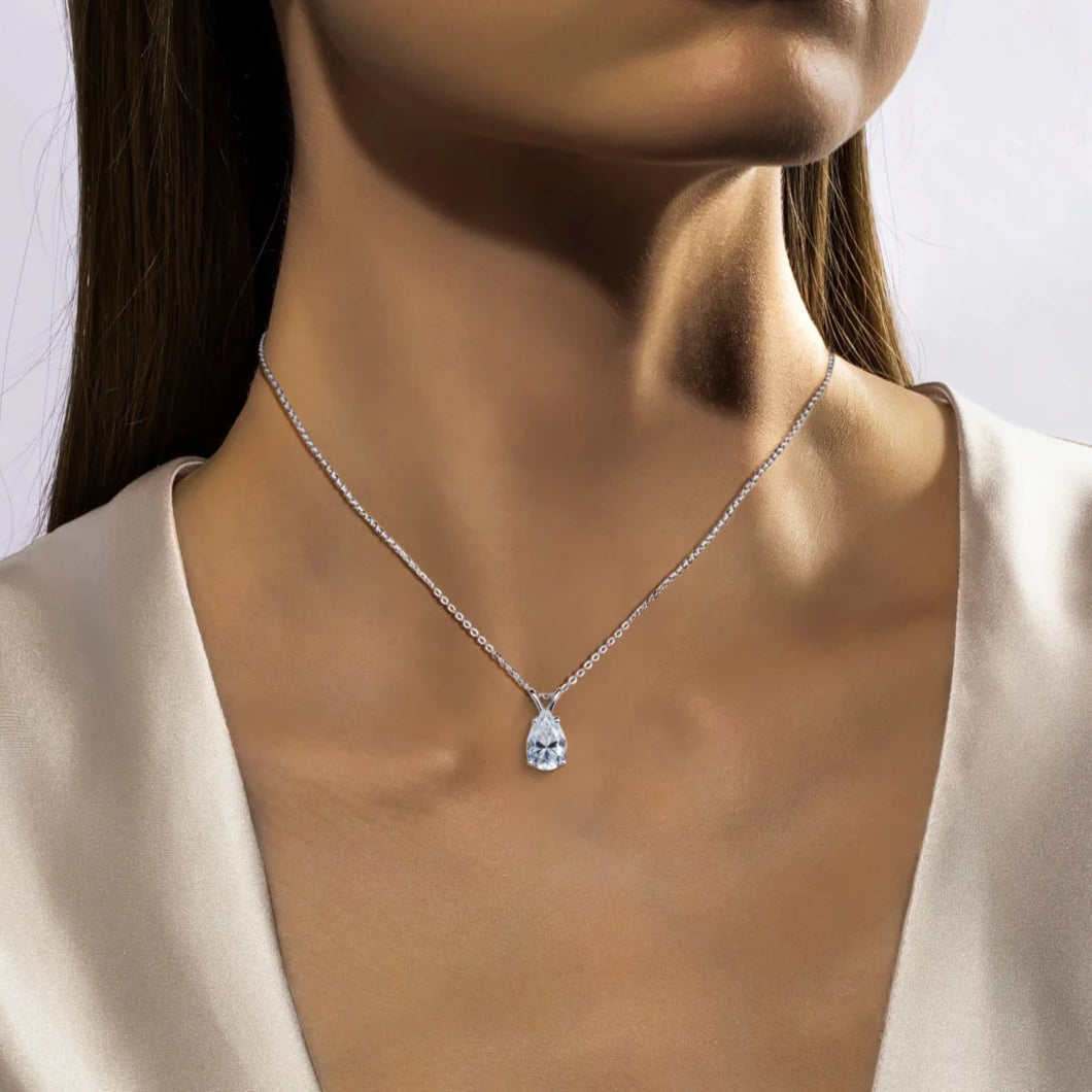 Woman wearing a necklace with a diamond pendant against a neutral background