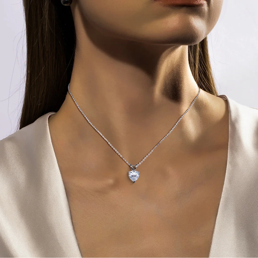 Close-up of a woman wearing a silver necklace with a heart-shaped pendant.