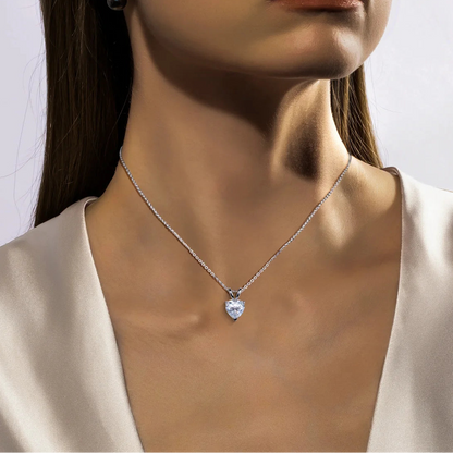 Close-up of a woman wearing a silver necklace with a heart-shaped pendant.