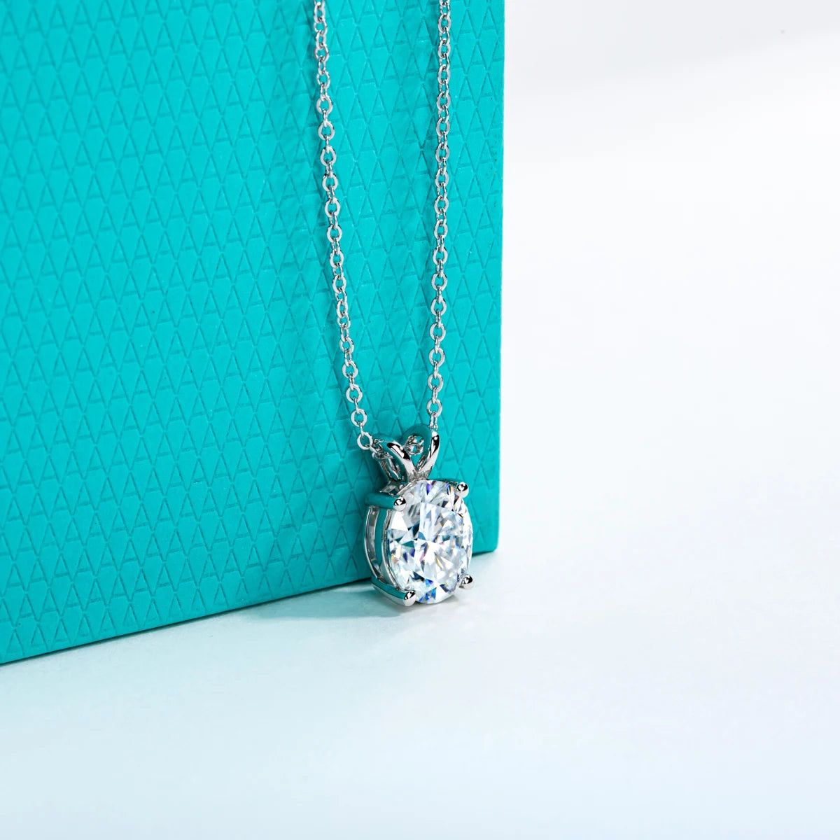 Silver necklace with a diamond pendant on a turquoise background