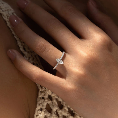Close-up of a hand wearing a diamond ring with a textured garment background