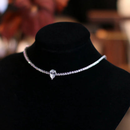 Silver necklace with a heart-shaped pendant on a black mannequin against a blurred background