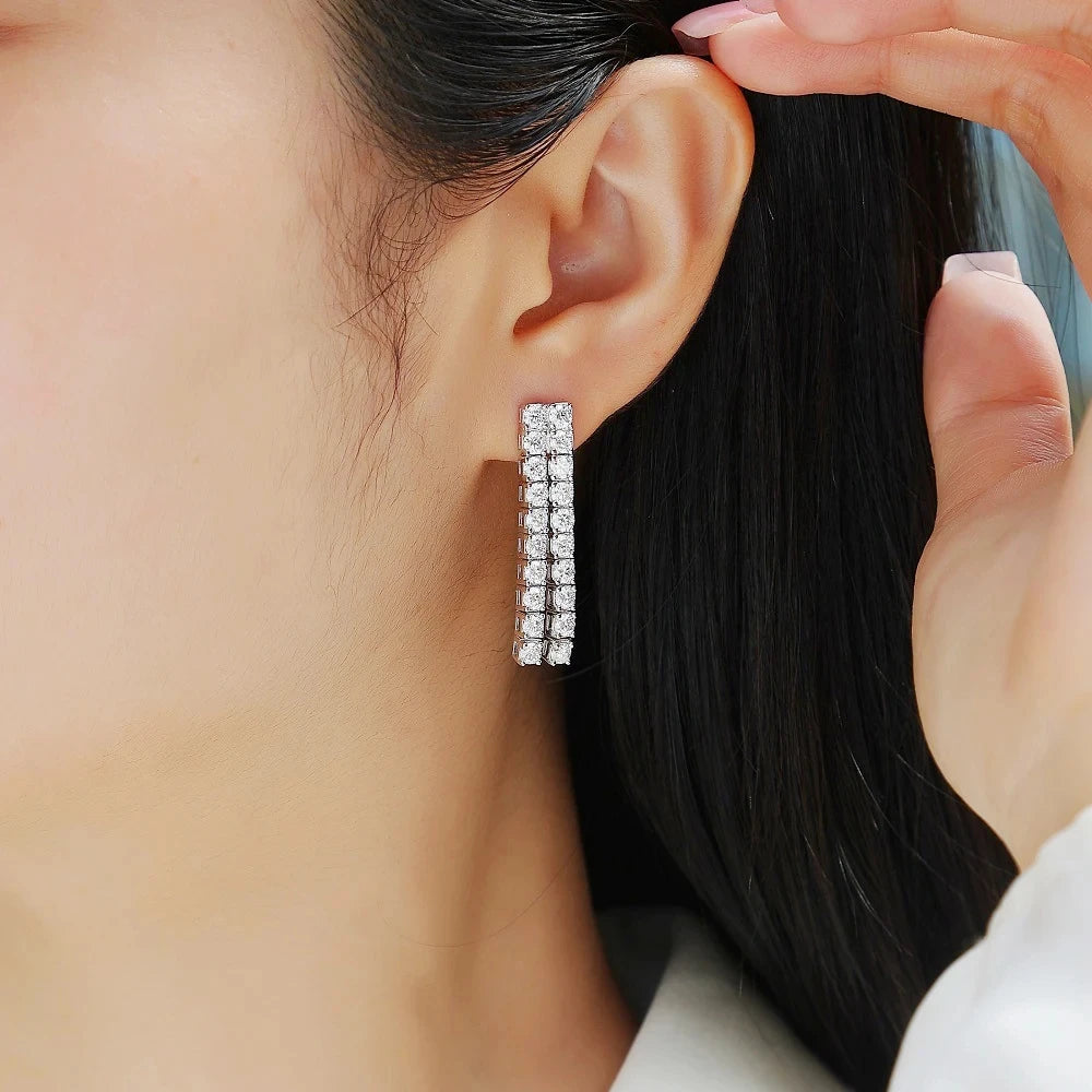Close-up of a person wearing a silver hoop earring with clear stones.