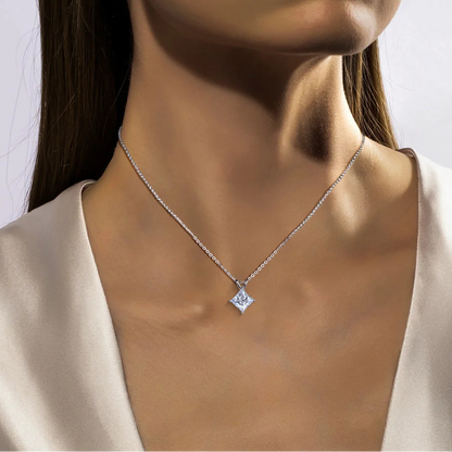 Close-up of a woman wearing a silver necklace with a diamond pendant against a neutral background