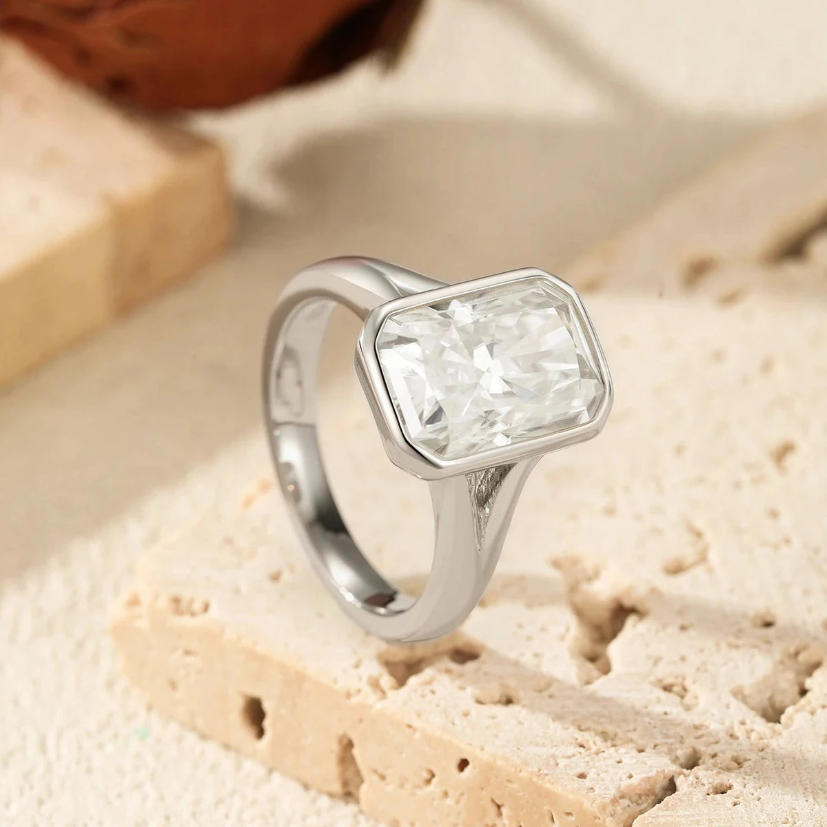 Silver ring with a clear gemstone on a textured beige surface
