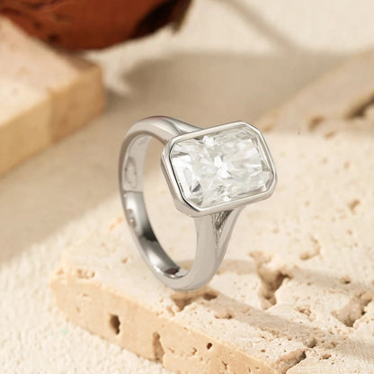 Silver ring with a clear gemstone on a textured beige surface