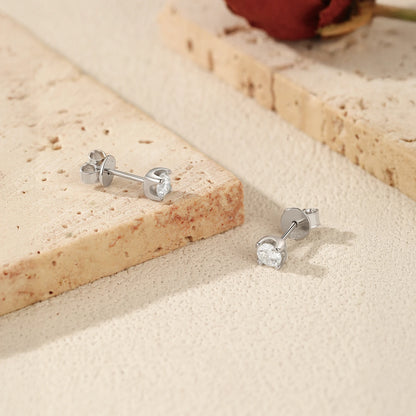 Silver stud earrings on a textured beige surface