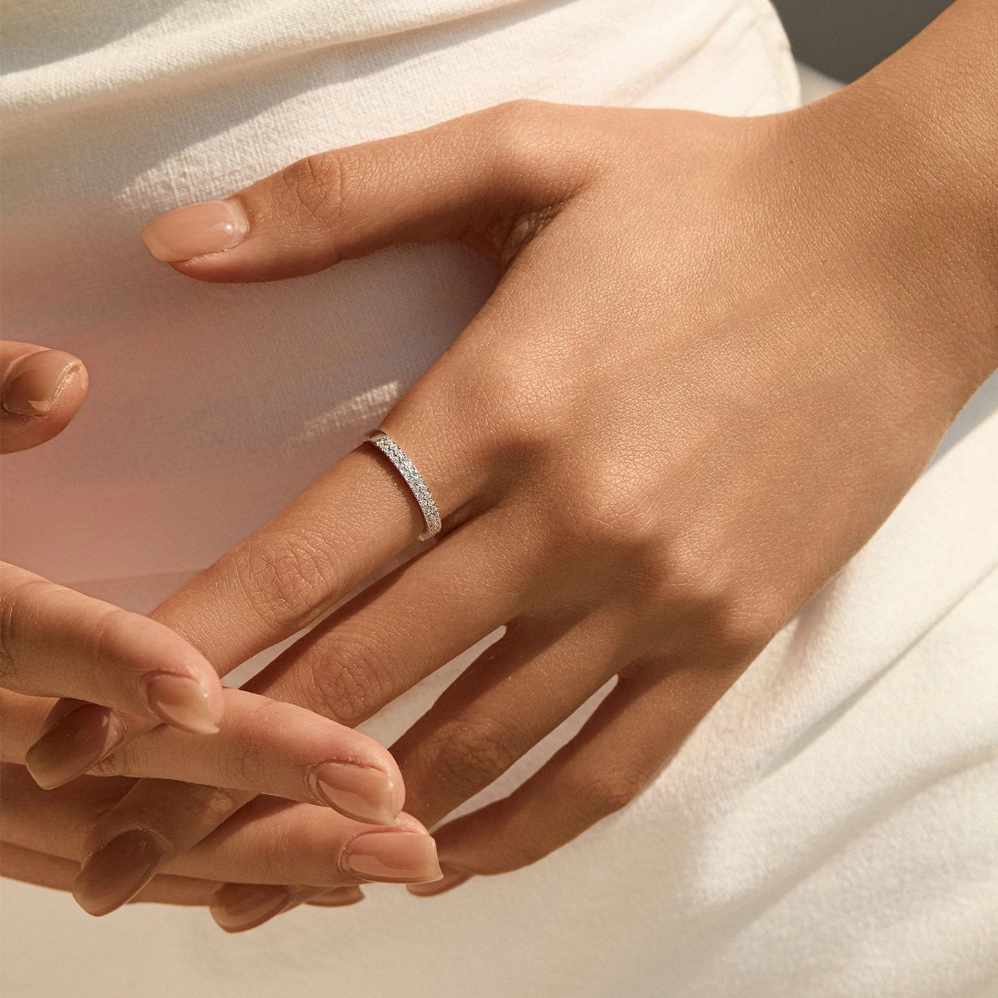 Close-up of a hand wearing a silver ring on a soft fabric background